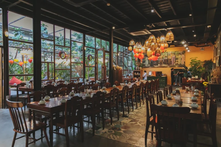 Góc trang trí bình hoa sen thanh tịnh bên cạnh ô cửa kính màu tròn tại nhà hàng Quán Bụi Garden
